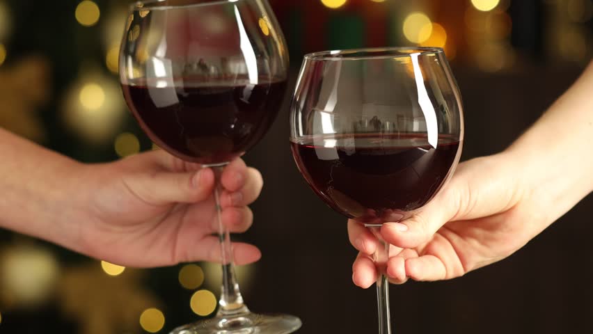 Women clinking glasses of red wine against blurred lights, closeup. Christmas and New Year celebration