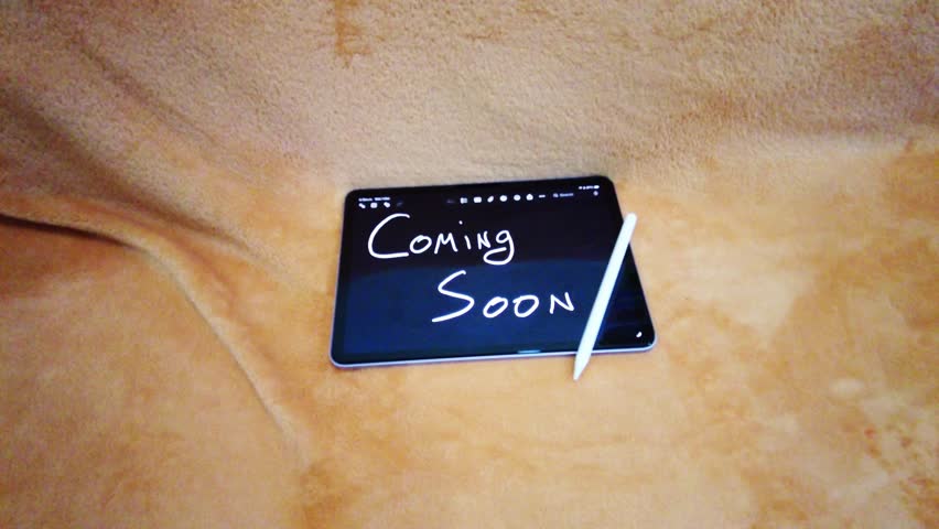 Cinematic 4K 60fps video of digital tablet showing handwritten, Coming Soon, in Dark Mode. Aesthetic teaser announcement on cozy orange background with stylus
