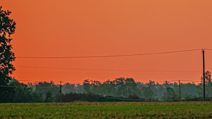 Giant sun close-up. Sun rising over field with vibrant red and orange sky. Timelapse.