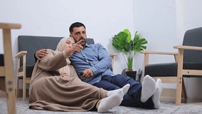 Muslim intimate couple relaxing together while watching TV in cozy living room - Powered by Shutterstock - Get 15% off with code: PIKWIZARD15