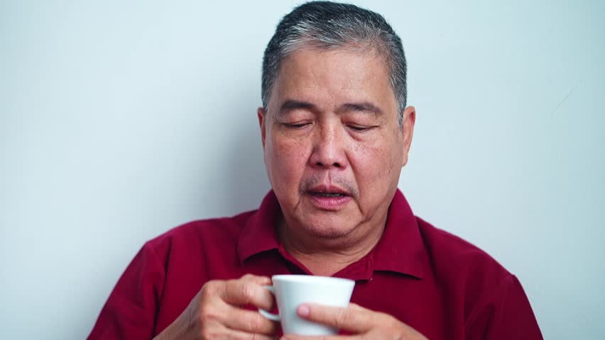 Close up Mature asian man enjoying comforting warm beverage savoring