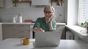 Middle aged businesswoman working multitasking on laptop, writing notes in notebook and gets distracted with smartphone, checking messages, answering call, having troubles with concentration and ADHD. - Powered by Shutterstock - Get 15% off with code: PIKWIZARD15