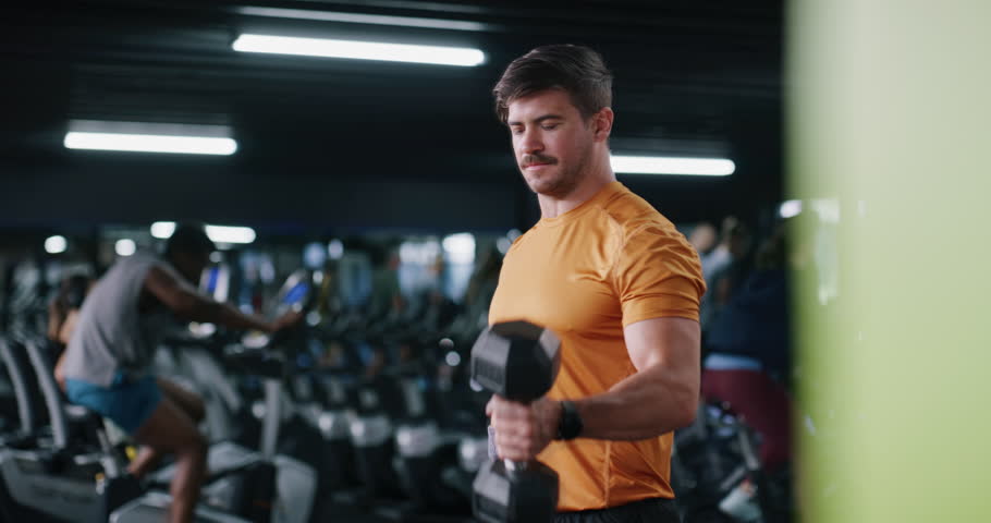 Dumbbell, fitness and intensity with man in gym for strength training or workout routine. Breathing, exercise and weightlifting with bodybuilder in health club for physical challenge or resilience