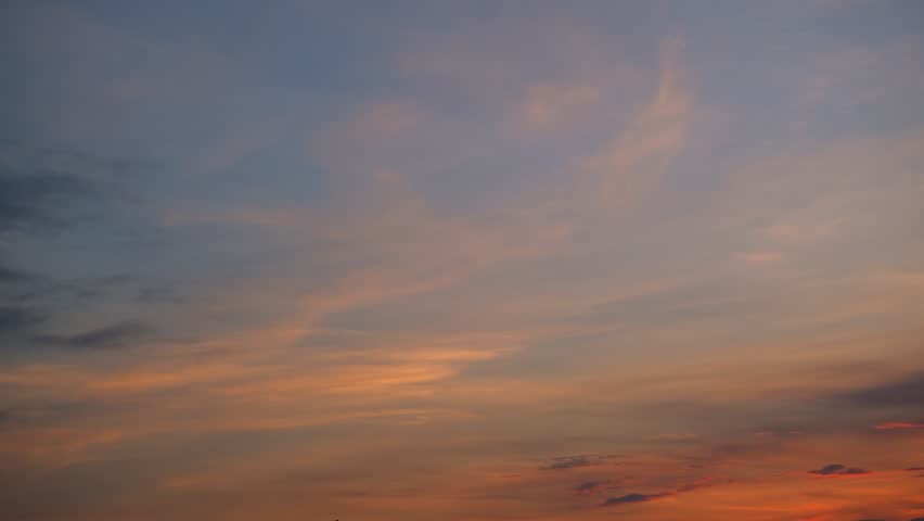 A warm sunrise sky timelapse featuring soft stratocumulus and thin cirrus clouds glowing in golden and pastel tones as the morning light spreads, capturing gentle cloud movement at dawn. Time-lapse.
