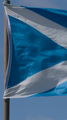Blue and white saltire flag flutters dynamically outdoors in bright daylight, captured in close-up