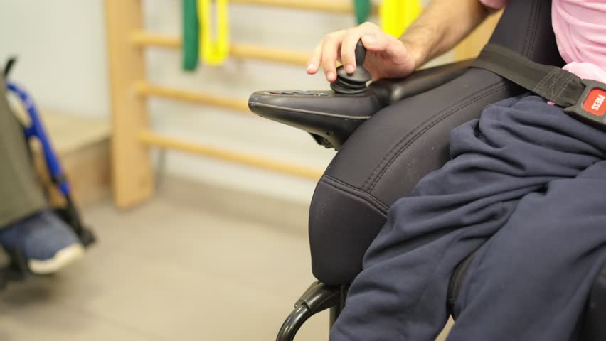 Person with physical disability operating electric wheelchair joystick