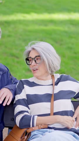 Mature couple talking and sitting on a park bench