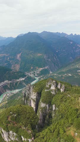 Vertical majestic aerial over the Daning River Gorge in Wuxi County, China. Captures the vast, steep, green mountains and the turquoise river valley below, emphasizing natural scale.