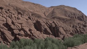 A truly special amalgamation of rocks forming a beautiful work of art in a desert mountain chain. In the foreground, some vegetation is visible under a bluish sky - Powered by Shutterstock - Get 15% off with code: PIKWIZARD15