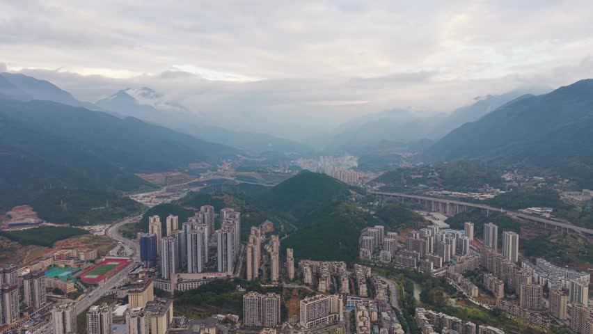Expansive drone shot of Wuxi’s modern skyline with dense high rises set against a lush mountain backdrop, urban growth and scenic contrast ideal for travel, architecture, and cityscape projects. China