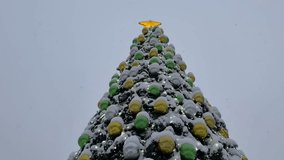 Happy New Year and Merry Christmas. Video of snowy city Christmas tree decorated with yellow and green glass balls and golden star at winter snowy day. Xmas and New Year holidays. Xmas background - Powered by Shutterstock - Get 15% off with code: PIKWIZARD15