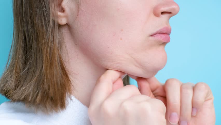 Female face with double chin close-up on blue background, side view.