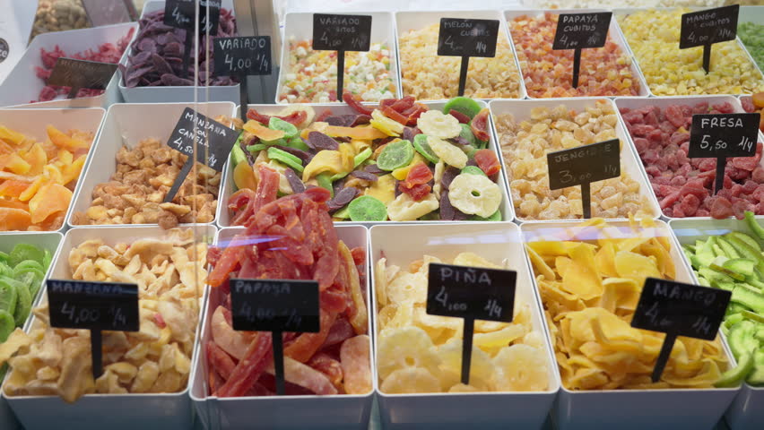 Close up of assorted dried fruits in trays with handwritten price tags in Spanish at the Central Market of Valencia, Spain