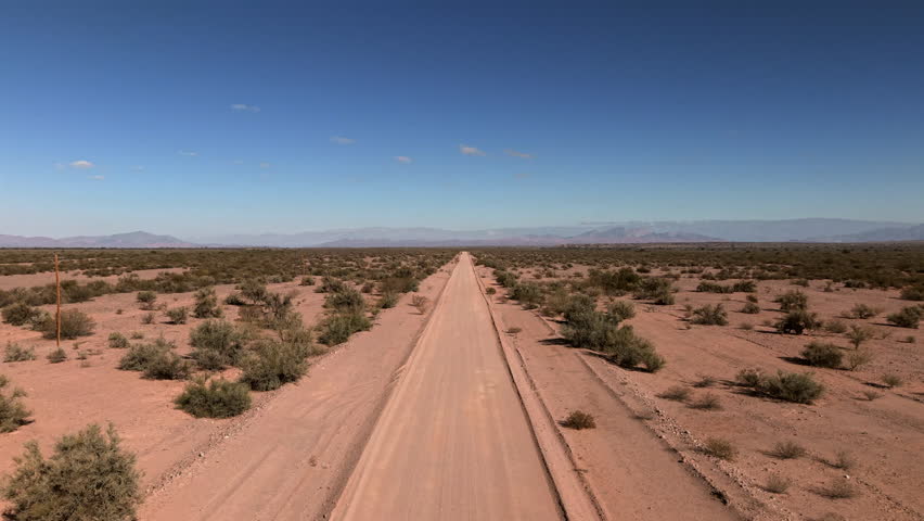 Desert road stretching towards horizon in La Rioja province, Argentina, symbolizing concepts of journey, adventure, freedom, solitude, and exploration, drone ascending