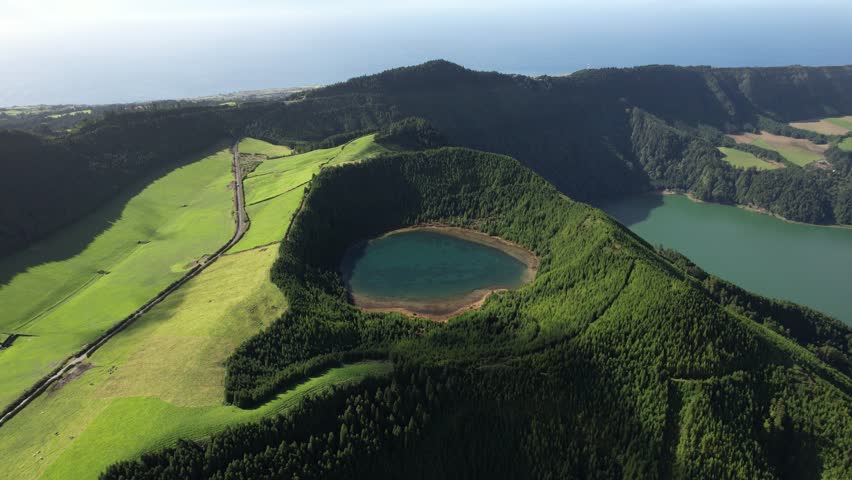 View over Lagoa Rasa with forested crater and Lagoa Verde in the distance in Sete Cidades on Sao Miguel island in the Azores as the drone moves right