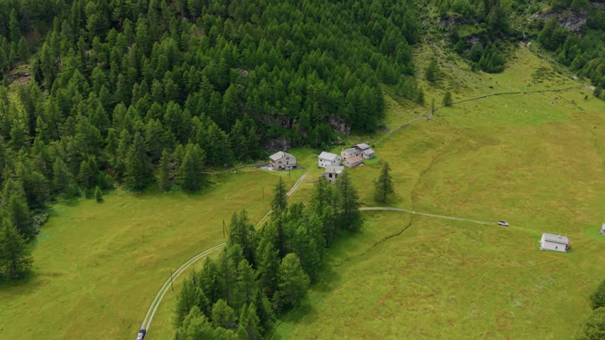 Aerial View of Small Alpine Hamlet Next to Dense Pine Forest in Valley