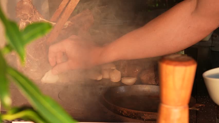 Slow-motion footage of steak, scallops and assorted food grilling on an outdoor barbecue. Thick smoke rises around the sizzling ingredients, creating a dramatic and flavorful atmosphere.