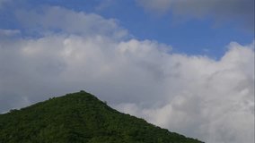 Clouds move steadily across bright blue sky above a lush green mountain covered in tropical forest while soft daylight shifts gently creating a calm open atmosphere. Serene landscape. - Powered by Shutterstock - Get 15% off with code: PIKWIZARD15