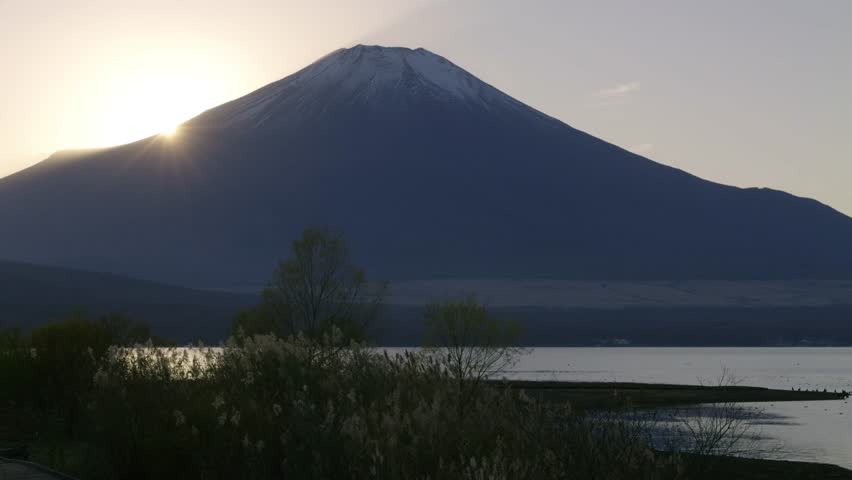 Sun disappearing behind Mt. Fuji with lake scenery at sunset