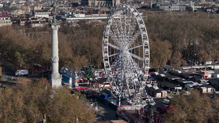 Aerial views of a lively riverside fair featuring a giant Ferris wheel in Bordeaux City