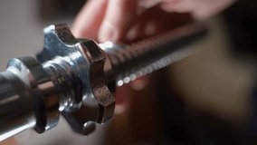 The barbell is spinning on a large thread of the rod, close-up. Unscrewing the rod nut on a blurred background - Powered by Shutterstock - Get 15% off with code: PIKWIZARD15