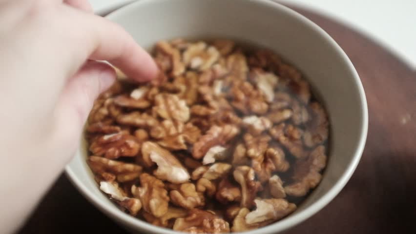 Closeup video of activated hydrated walnuts. Nuts in a bowl filled with water. Healthy snack rich in fibre, fat and nutrients.