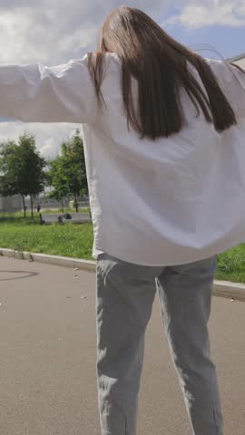 Beautiful girl with long hair rollerblading in park. Roller skating quads - popular and safe type of recreation. Vertical. High quality 4k footage