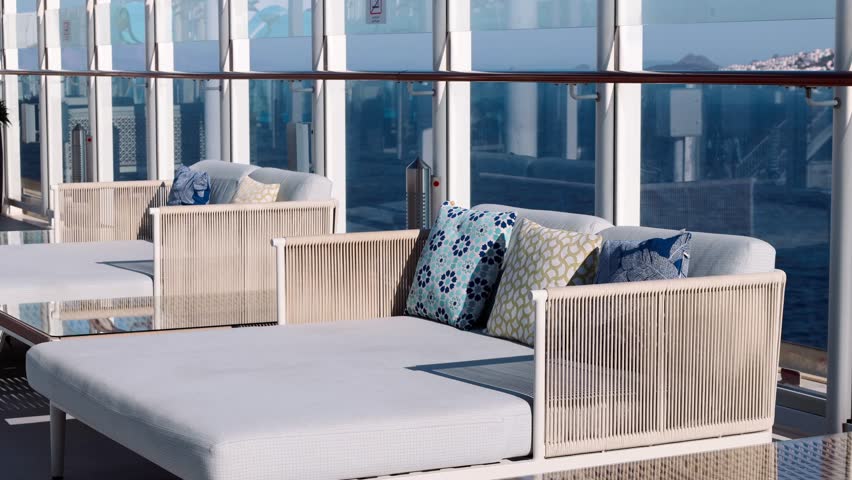 Open deck with cushioned seating glass railing bright sky clean surfaces minimal design and calm spacious atmosphere.