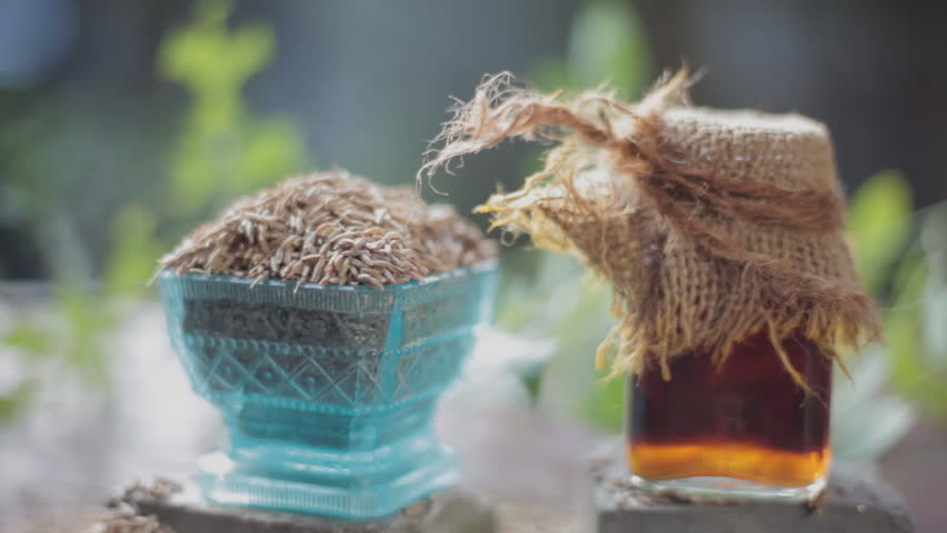 Black cumin seeds, shah jerra, Nigella sativa  and its extracted water in a transparent glass on brown wooden surface.