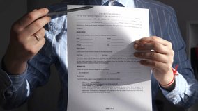 Closeup of a businessmans hands carefully examining a rental agreement, tracing fingers along contract terms and conditions. This professional footage demonstrates thorough document review and due - Powered by Shutterstock - Get 15% off with code: PIKWIZARD15