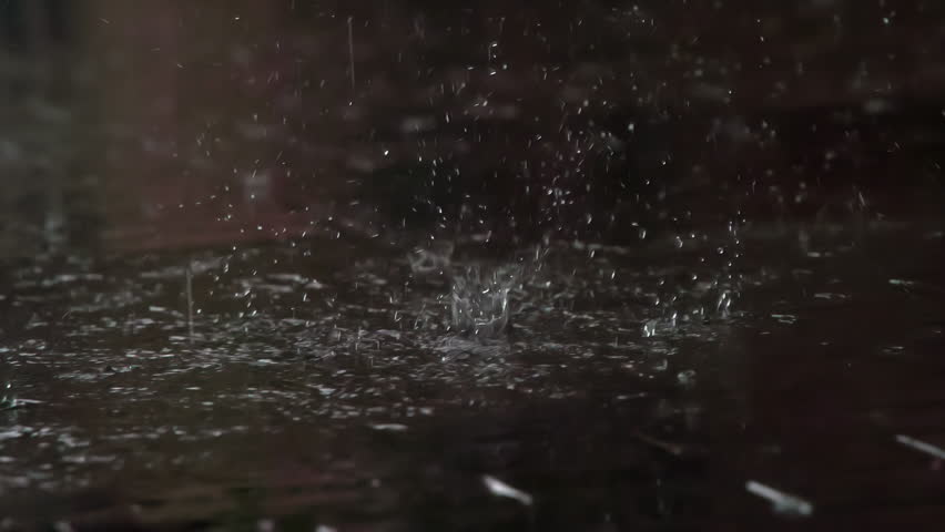 Drops of Rain Fall on the Sidewalk. Drops of rain fall from the roof onto a granite paving slab