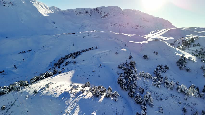 A peaceful snowy mountain landscape featuring a gondola line, winding ski slopes, and pine trees under soft sunlight. Ideal for themes of winter sports, alpine travel, nature and outdoor adventure.
