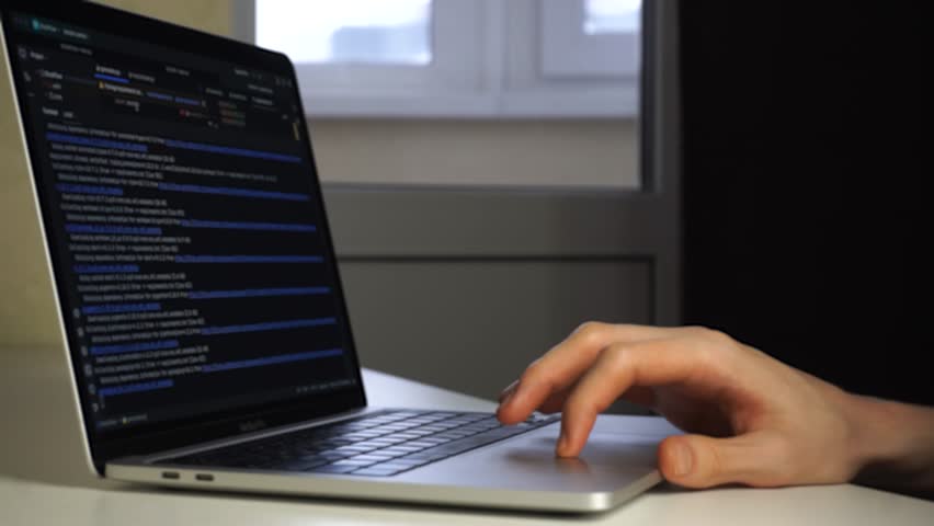 A man types rapidly on a laptop, his fingers moving across the laptop as he works. The man in a focused posture uses the laptop to complete his tasks efficiently.