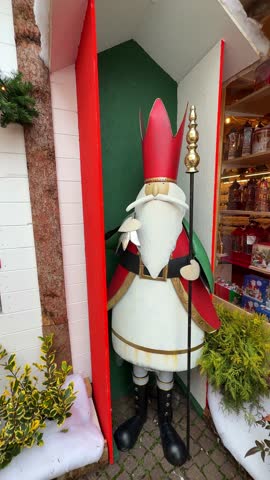 Life-size brightly painted metallic king statue with crown and scepter at a Christmas street market. Festive holiday decor adding royal charm and vibrant seasonal atmosphere