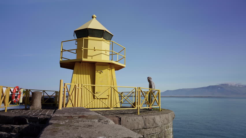 Man Standing by Yellow Lighthouse