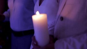 Close-up of a mans hands holding a large, thick white candle. The scene is filled with purple tones. - Powered by Shutterstock - Get 15% off with code: PIKWIZARD15