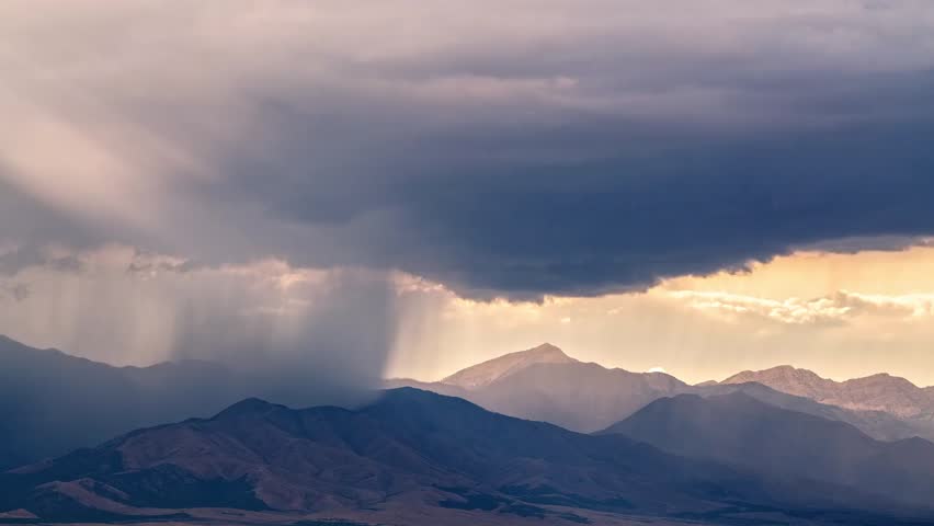 Dramatic Clouds Loom Over Majestic Mountains During Sunset