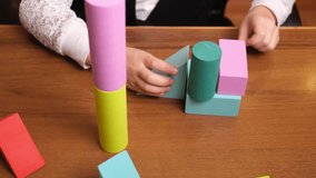 Little girls hands building a wobbly tower from soft pastel blocks on wooden table, shapes constantly collapsing, playful trial and error moment for early education, parenting blogs and toy brands - Powered by Shutterstock - Get 15% off with code: PIKWIZARD15