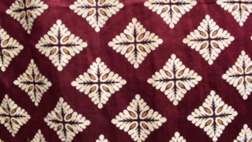 velvet fabric with a repeating diamond pattern made of ornate cream and gold motifs arranged in neat rows across the surface. useful for backgrounds