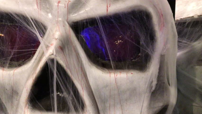 Spooky halloween scene featuring a bloody skull with flashing eyes and a glowing jack o