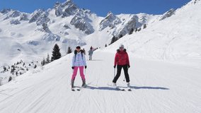 Women learning to ski together. Friends practicing parallel turns on snow. Bright blue sky over snow capped alpine slopes. Two women in colorful gear enjoy skiing among majestic mountain peaks - Powered by Shutterstock - Get 15% off with code: PIKWIZARD15