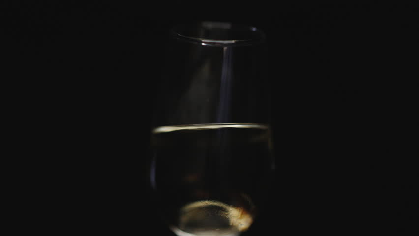 
Detail of a wine glass with chamomile on a black background with lights shining through the glass