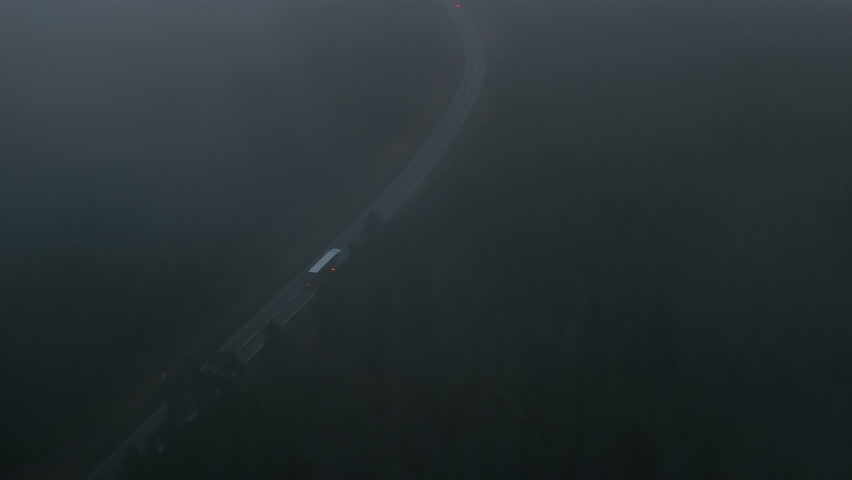 Silent nighttime drive through misty countryside, Solo freight vehicle moving along winding rural road in fog