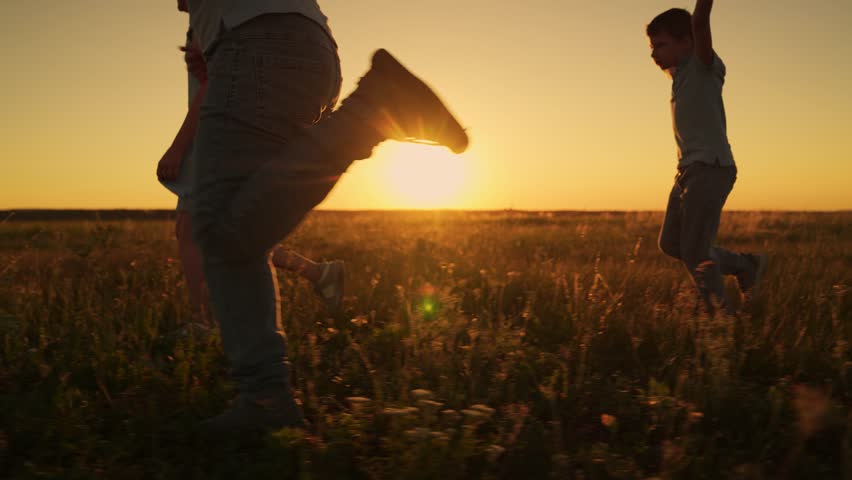 Children play run in park in summer. Happy group of children running through grass in field in sun. Kids team run across grassy lawn. Children playing outdoors. Happy family, teenagers running in park