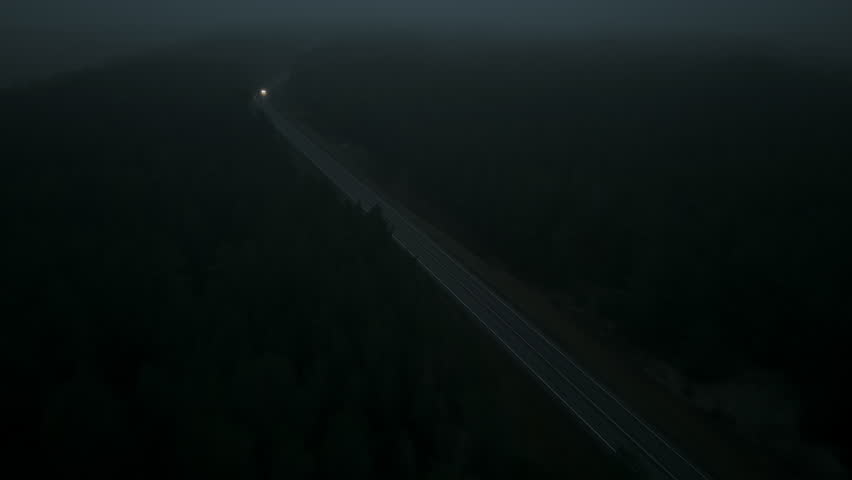 Aerial view of highway repair crew working overnight with safety barriers and lighting in forested zone