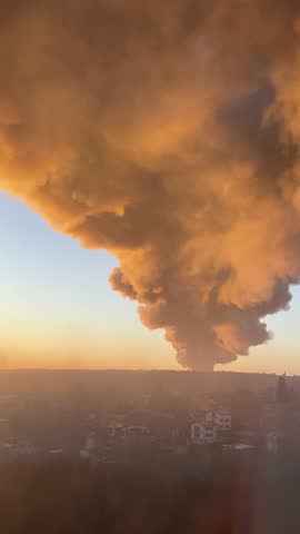 A plume of smoke rises in the sunrise after a Russian missile hit energy infrastructure and warehouses in Ukraine. Vertical video.