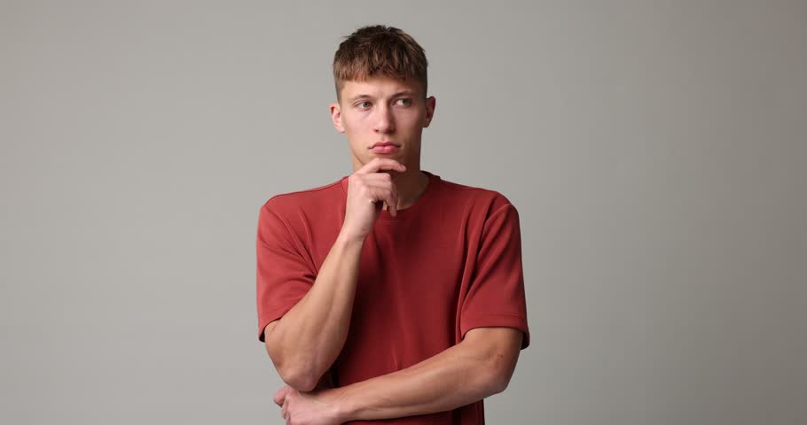 Thoughtful young man posing on grey background