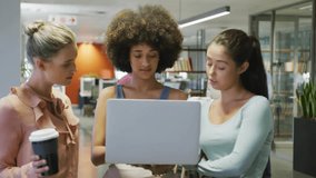 Three women colleagues leaning around laptop, left tapping and social badges rising for marketing. Office, collaboration, openplan, workspace, modern, discussion, focus - Powered by Shutterstock - Get 15% off with code: PIKWIZARD15