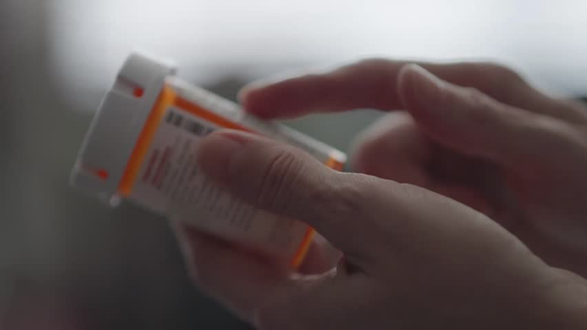 A woman carefully reads the instructions on her prescription bottle, ensuring proper dosage and safety before taking her medication.
