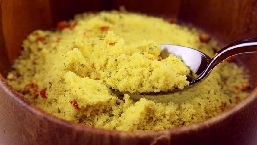 Yellow chicken stock powder seasoning taking with a spoon from a bowl close up